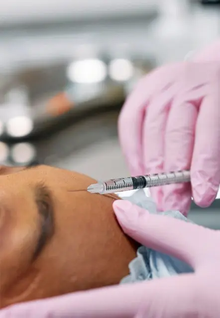 A person getting an injection into the face of another person.