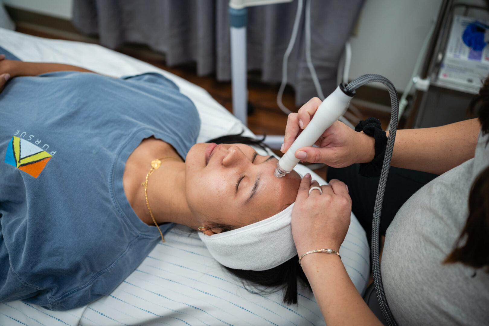 A woman getting her face cleaned with an electric device.