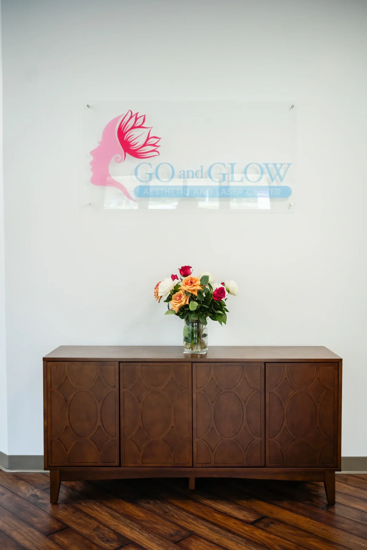 A vase of flowers on top of a wooden cabinet.