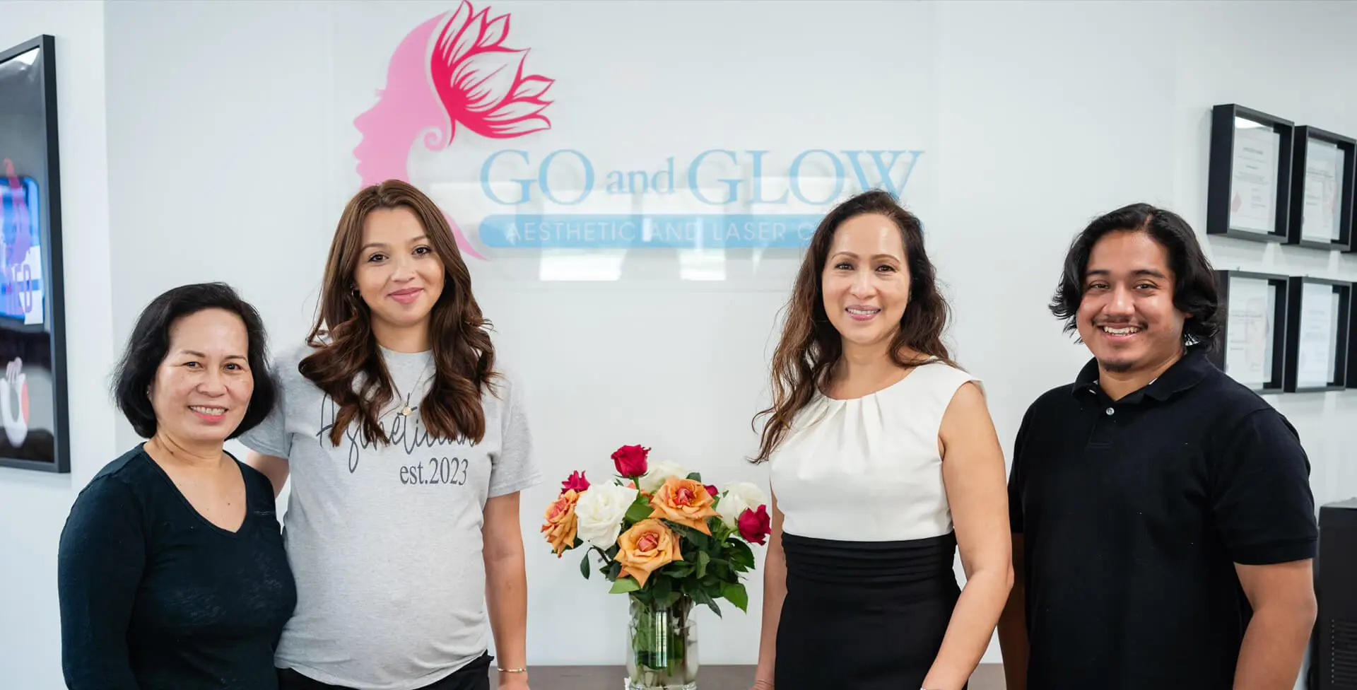 Three women standing in front of a sign with flowers.