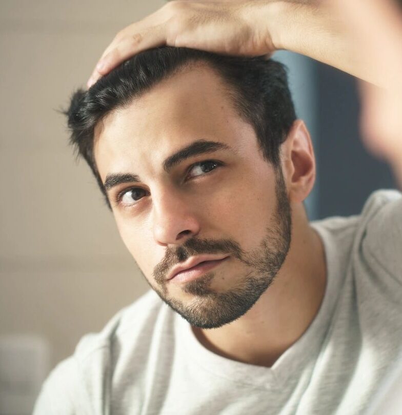 A man with his hand on his head looking at the camera.